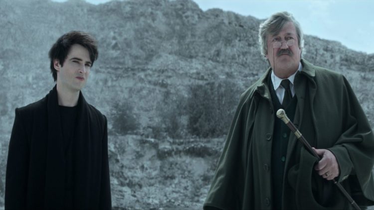 Tom Sturridge as Dream, Stephen Fry as Gilbert standing in front of a rocky expanse in The Sandman