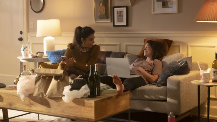 Ginger Gonzaga as Nikki Ramos and Tatiana Maslany as She-Hulk/Jennifer "Jen" Walters sitting on a sofa in She-Hulk: Attorney at Law