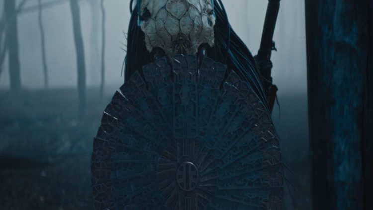 Dane DiLiegro as The Predator with a shield in the forest in Prey