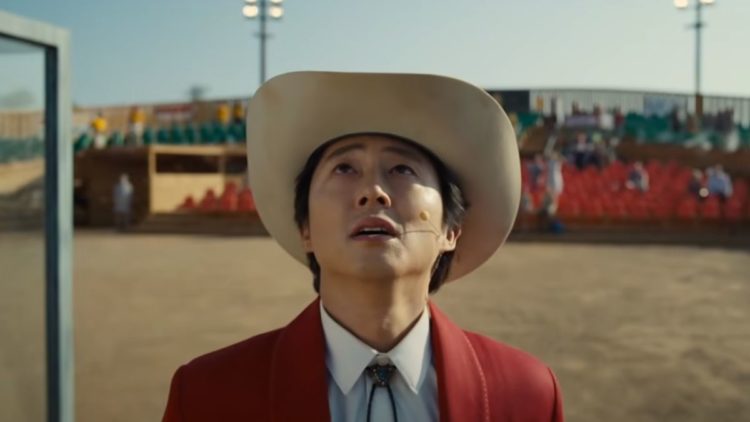 Steven Yeun as Jupe starring up at the sky in a cowboy hat in Nope
