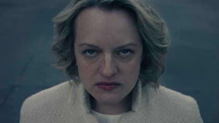 June (Elisabeth Moss) in close up shot wearing white coat in The Handmaid's Tale