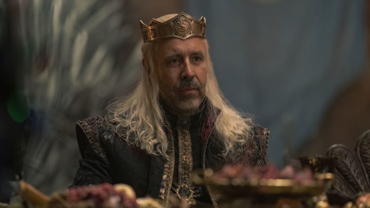 Paddy Considine as Viserys sitting at a food table in House of the Dragon