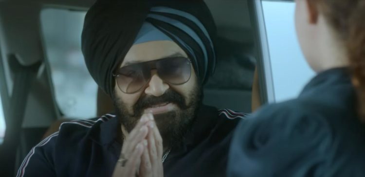 Mohanlal as Lucky Singh puts his hands together whilst wearing sunglasses and sat in a car