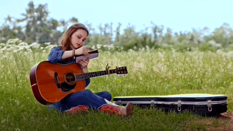 Savannah Lee May as Hailey playing the guitar in a field in A Cowgirl's Song