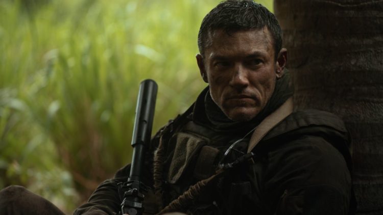 Luke Evans sitting holding a gun in Echo 3
