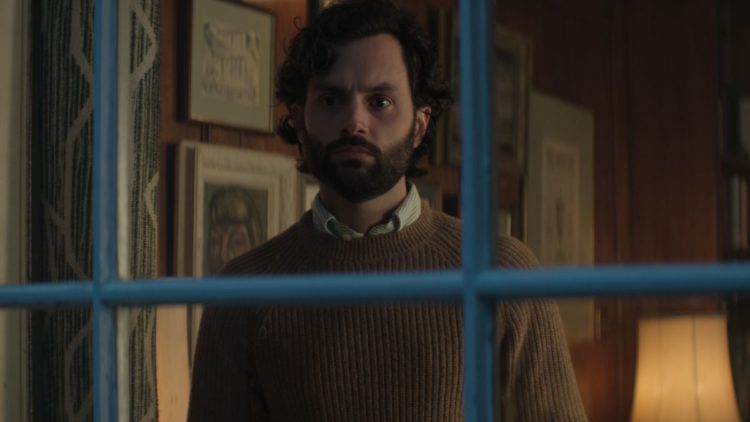 Penn Badgley as Joe Goldberg in a tweed jacket with a woman's hands on his face in