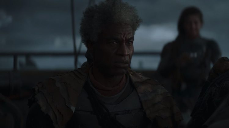Charles Parnell as a Mandalorian captain on Mandalore sitting at a table in dark brown uniform in The Mandalorian episode 7