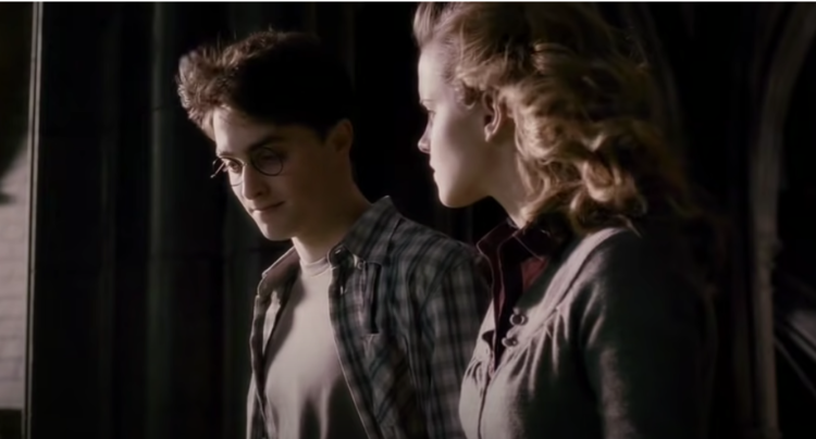 Daniel Radcliffe as Harry wearing chequered shirt and grey tee next to Emma Watson as Hermione in Harry Potter And The Half-Blood Prince